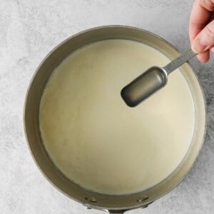 a person pouring milk into a pan.