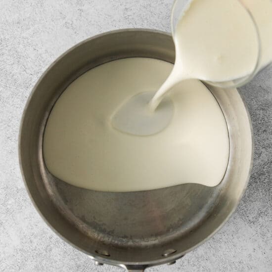 a person pouring milk into a pan.
