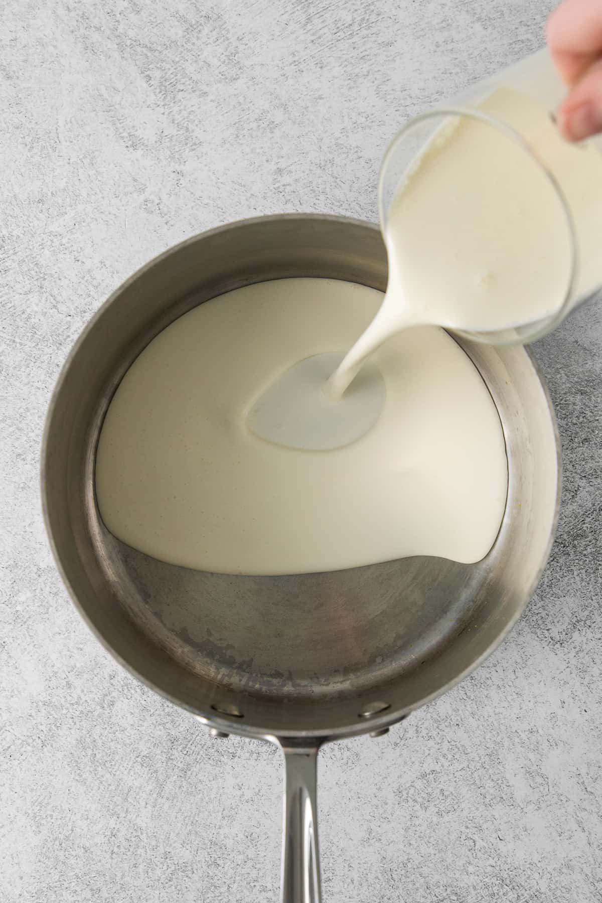 Heavy cream being poured in a saucepan.