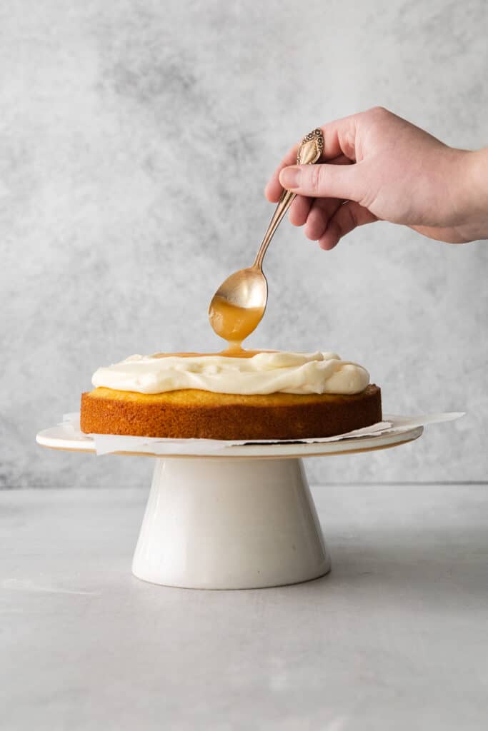 a hand is dipping a spoon into a cake.