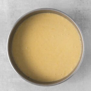 a yellow batter in a metal pan on a grey surface.