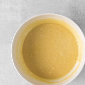 a bowl of yellow batter on a white surface.