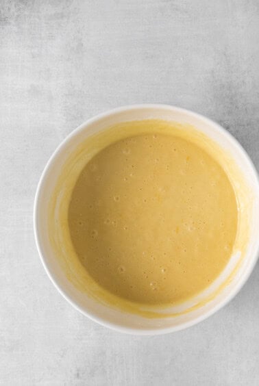 a bowl of yellow batter on a white surface.