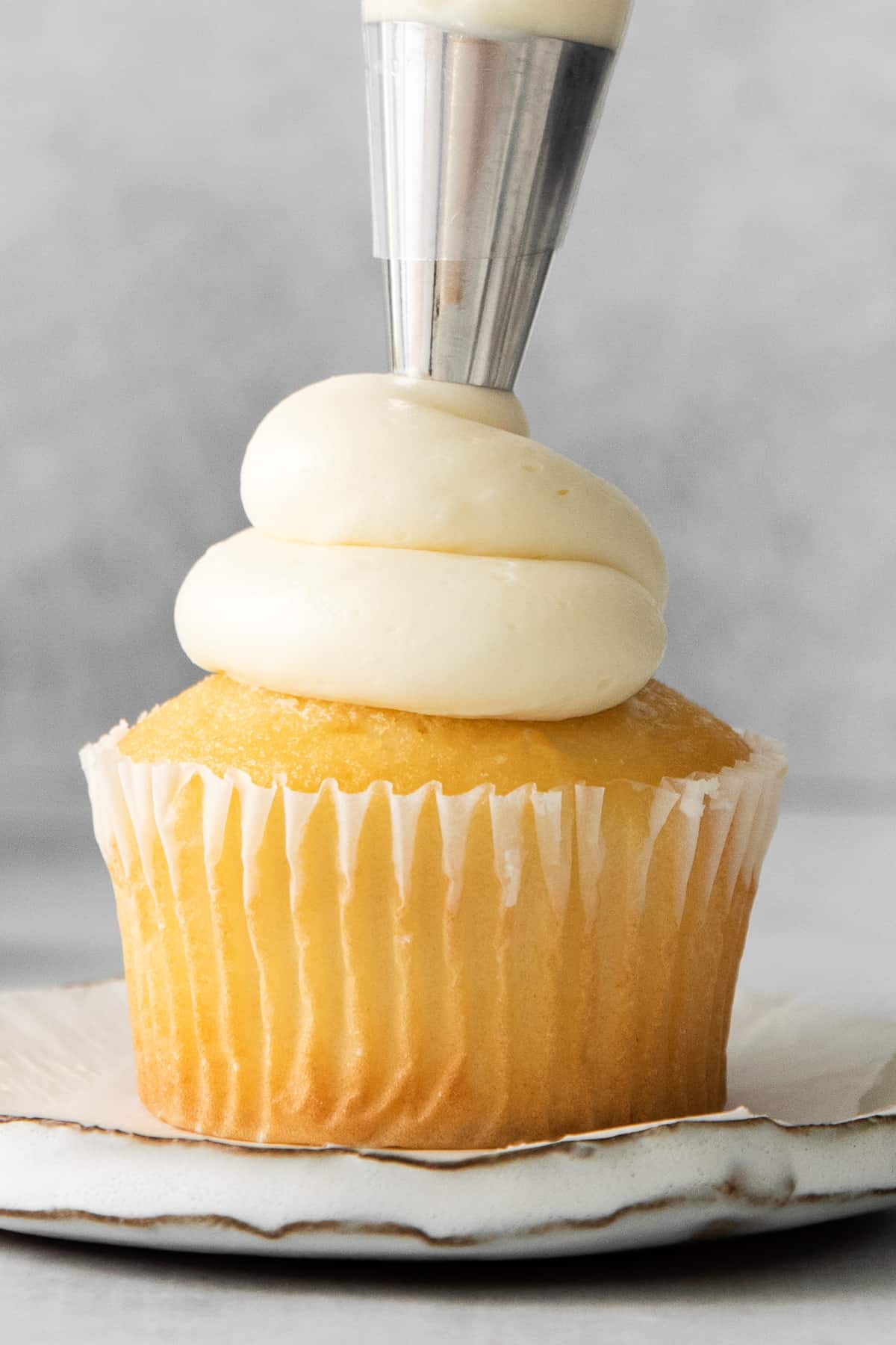 Mascarpone frosting being piped onto a cupcake.