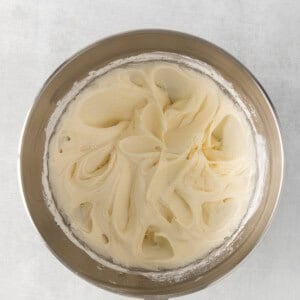 whipped cream in a metal bowl on a white background.