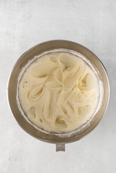whipped cream in a metal bowl on a white background.