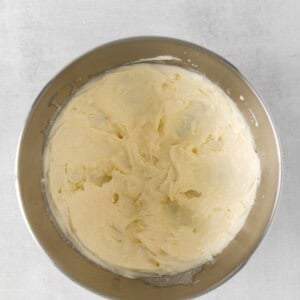 whipped cream in a metal bowl on a white background.