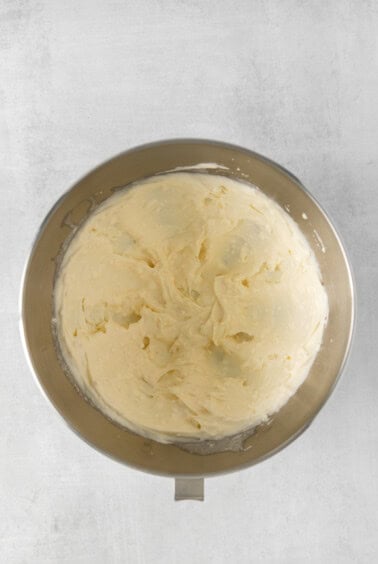whipped cream in a metal bowl on a white background.