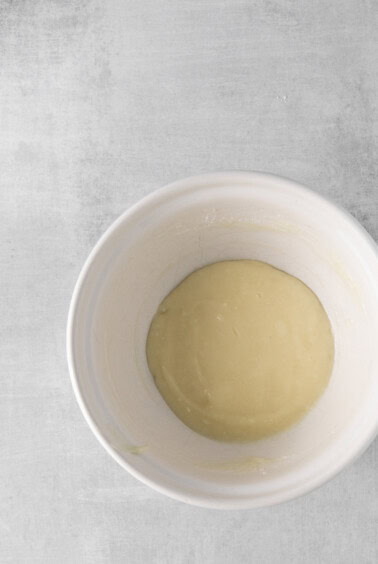 a white bowl with a yellow liquid in it.