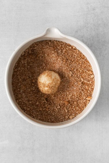 an egg in a white bowl of granulated sugar.