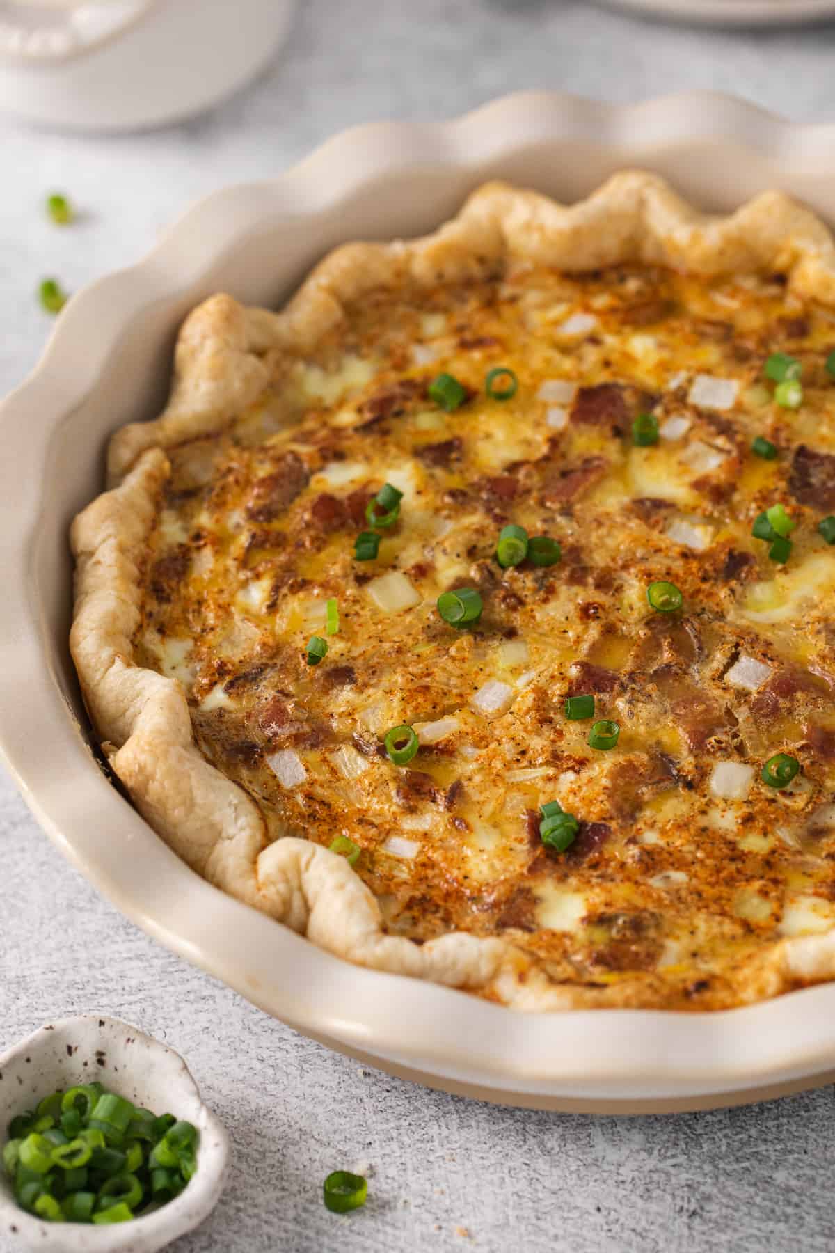 Quiche lorraine topped with green onions.