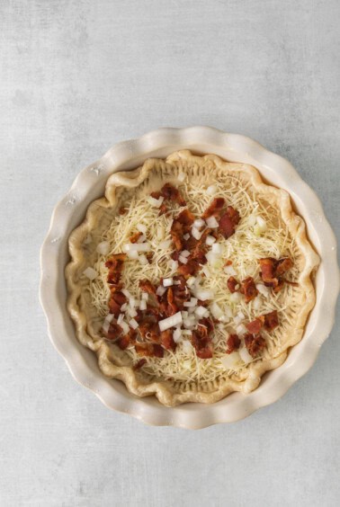 a pie with bacon and onions in a white dish.