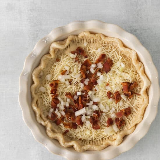a pie with bacon and onions in a white dish.