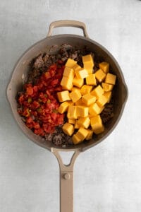 a frying pan filled with meat, cheese and tomatoes.