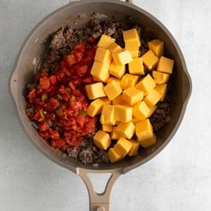 a frying pan filled with meat, cheese and tomatoes.