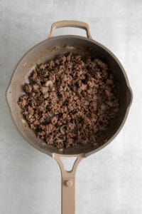 a frying pan filled with ground beef and onions.