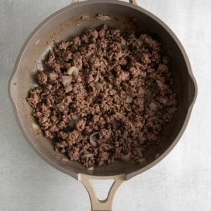 a frying pan filled with ground beef and onions.