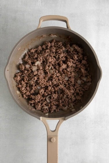 a frying pan filled with ground beef and onions.