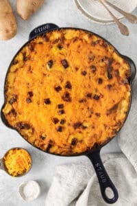 cheesy sweet potato casserole in a cast iron skillet.