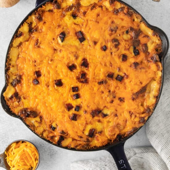 cheesy sweet potato casserole in a cast iron skillet.