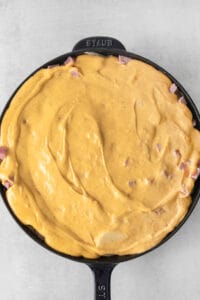 a skillet filled with cheese and ham.