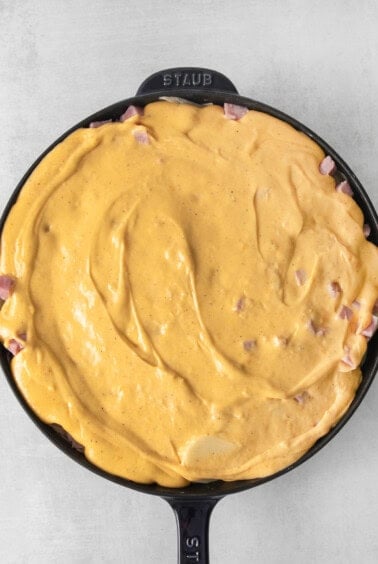 a skillet filled with cheese and ham.