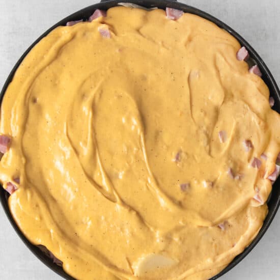 a skillet filled with cheese and ham.