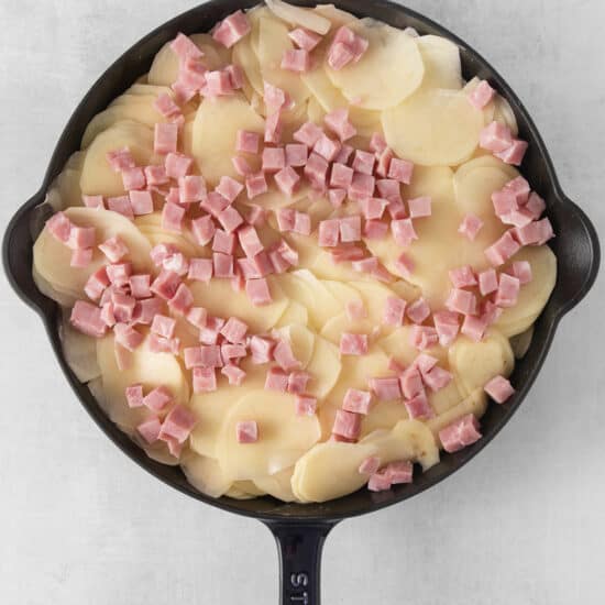 ham and potatoes in a skillet on a white background.
