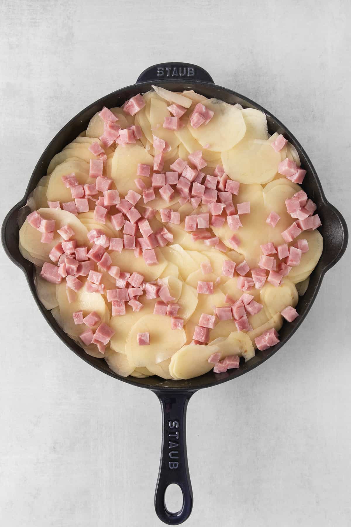 Ham and scalloped potatoes in a skillet before adding cheese.