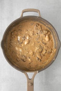 a skillet filled with mushrooms and gravy.