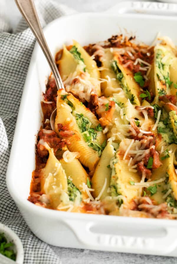 Stuffed shells in a white baking dish with meat sauce.