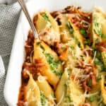 stuffed shells with spinach and bacon in a white dish.