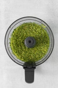 a food processor filled with green pesto.