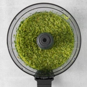 a food processor filled with green pesto.