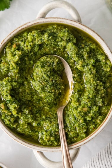 Cilantro pesto in a bowl with a spoon.
