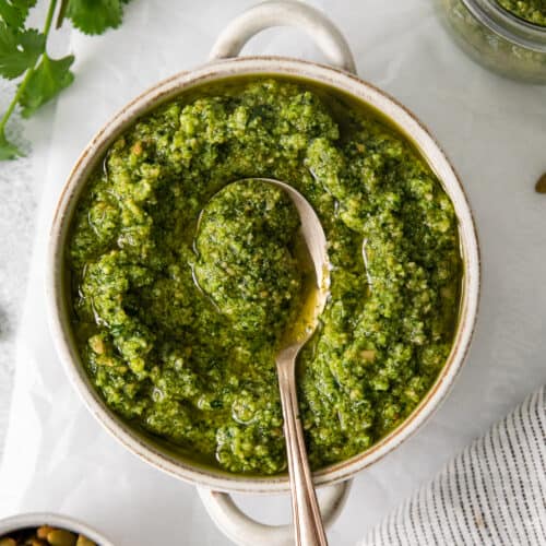 Cilantro pesto in a bowl with a spoon.
