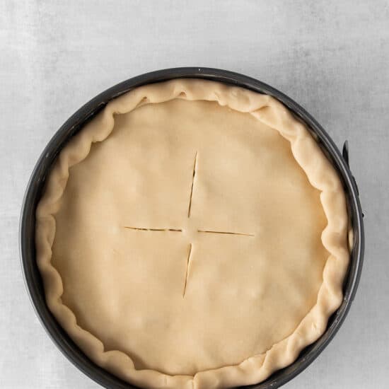 a pie crust in a pan on a grey background.
