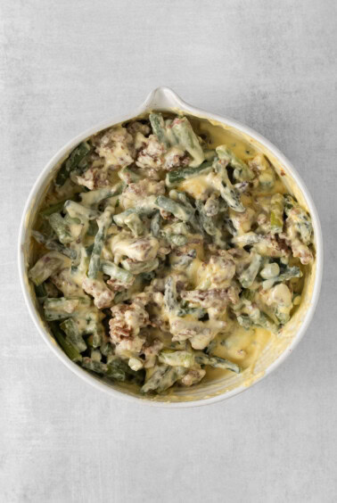 a white dish with green beans and meat in it.