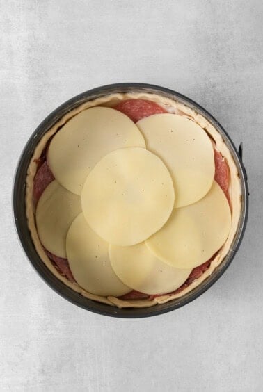 a pie with slices of cheese in a pan.