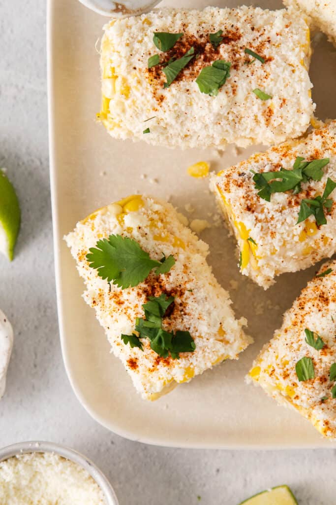 Elote corn on a plate topped with cilantro.