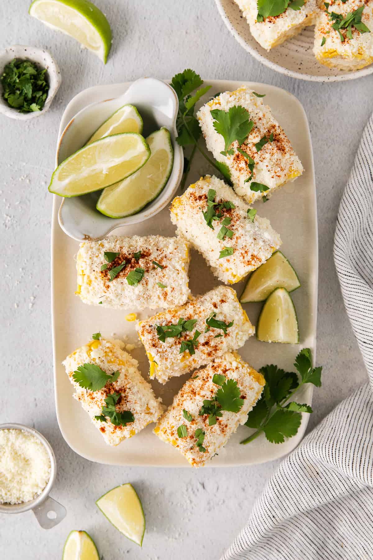 Elote corn on a plate with slices of lime.