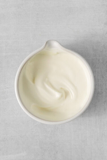 a white bowl of yogurt on a gray surface.