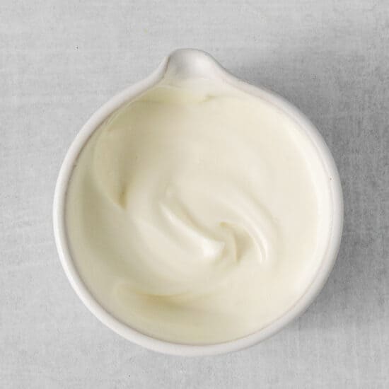 a white bowl of yogurt on a gray surface.