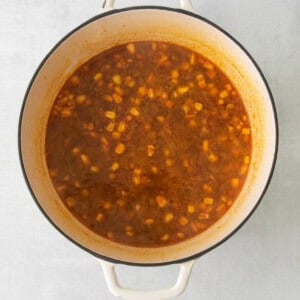 a pot of soup with beans and corn on a white background.