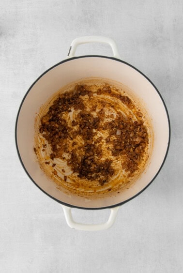 a pot with a brown sauce on a white background.
