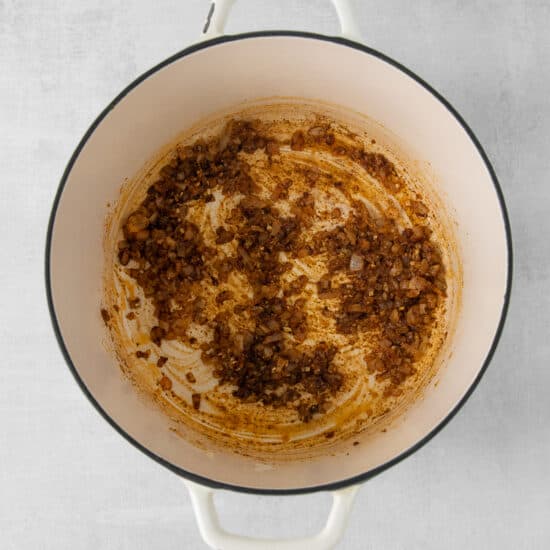 a pot with a brown sauce on a white background.