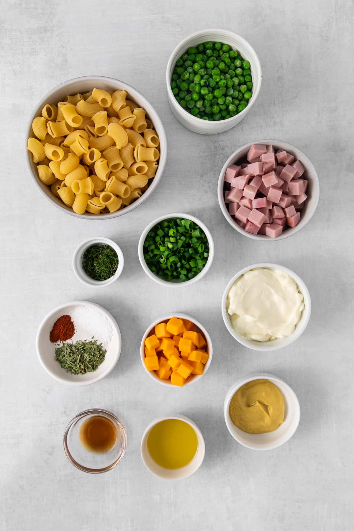 Ingredients for ham and pea pasta salad in bowls.