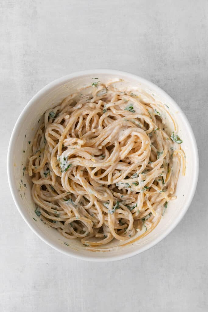 Pasta with ricotta sauce in a bowl with fresh herbs.