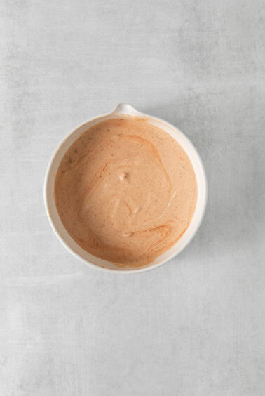 a bowl of sauce on a white surface.