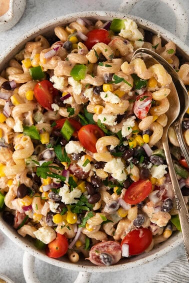 a bowl of pasta salad with black beans, tomatoes and corn.